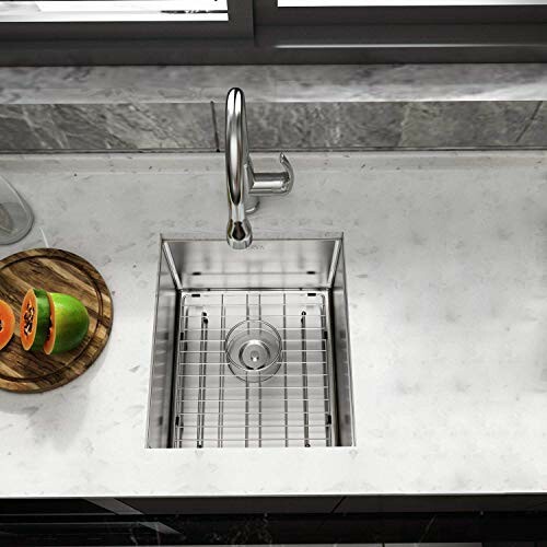 Overhead view of a modern kitchen sink with a marble countertop and sliced fruit on a wooden board.